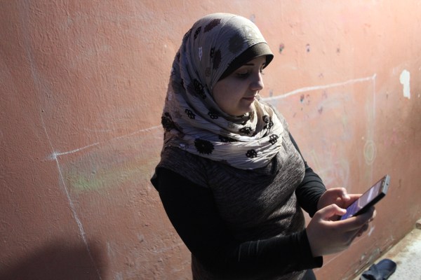 Amal Haddad holds her mother’s cell phone in her hand, with the app, “Smart Dictionary,” that she uses to help her with her homework.